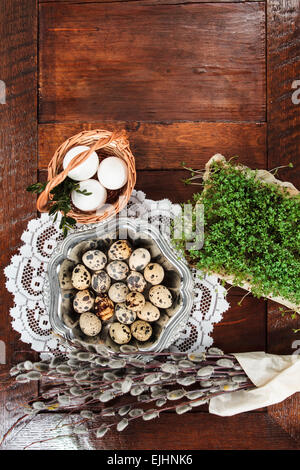 Ostern-Zusammensetzung von Willow Zweige mit Kätzchen, Kresse, Wachteleier in Metall Schale und Ostern Korb mit Eiern, eingestellt auf alten hölzernen Stockfoto
