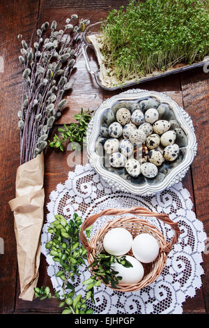 Ostern-Zusammensetzung von Willow Zweige mit Kätzchen, Buchsbaum, Wachteleier in einem Metall-Teller, Osterkorb mit Eiern und Kresse, eingestellt auf Stockfoto