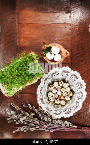 Ostern-Zusammensetzung von Willow Zweige mit Kätzchen, Kresse, Wachteleier in Metall Schale und Ostern Korb mit Eiern, am Tisch Stockfoto