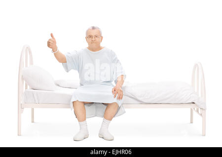 Studio Schuss eine mündige Patient sitzt auf einem Krankenhausbett, einen Daumen aufgeben und in die Kamera schaut Stockfoto