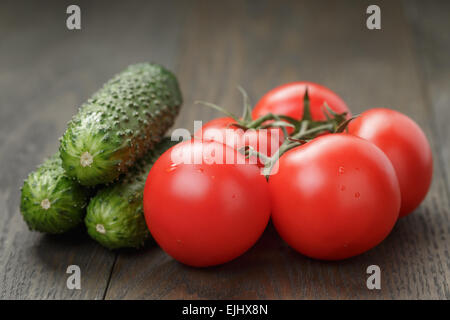 Reife nasse Tomaten auf Wein und Gurken auf Holztisch Stockfoto