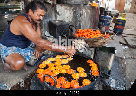 Man drückte einen Beutel mit Gemisch zu braten und Jalebi und Imarti in einer großen Pfanne Kochen Stockfoto