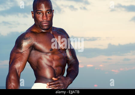 Silhouette eines Bodybuilders posiert auf den Sonnenaufgang am Strand, Ausbildung in den Morgen, starken Mann zeigt seine Muskeln Stockfoto