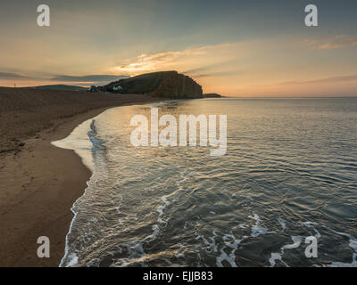 Sonnenaufgang am Sandstrand in West Bay in Dorset mit Blick auf den Klippen Stockfoto