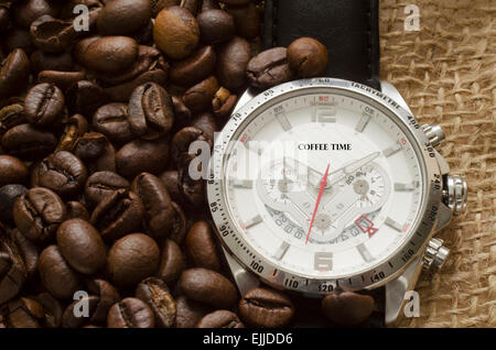 Silberne Uhr mit schwarzen Ledergürtel und Kaffeebohnen auf Leinwand Stockfoto