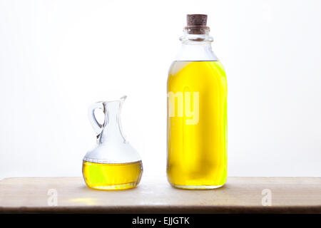 Olivenölflasche und Menage isoliert auf weißem Hintergrund platziert auf Holzuntergrund Stockfoto