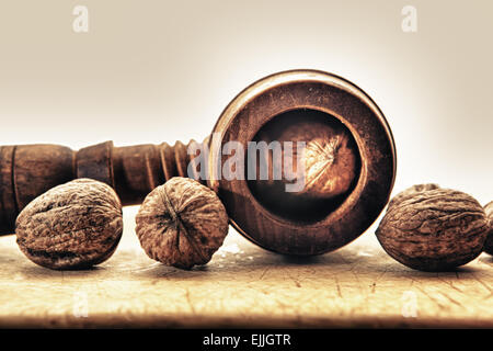 Walnüsse und alten hölzernen Nussknacker isoliert auf weißem Hintergrund platziert auf Holzuntergrund Stockfoto