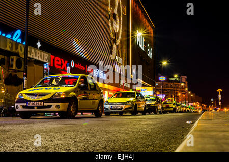 Eine Reihe von Taxi Autos vor Einkaufszentrum in Bukarest in der Nacht. Stockfoto