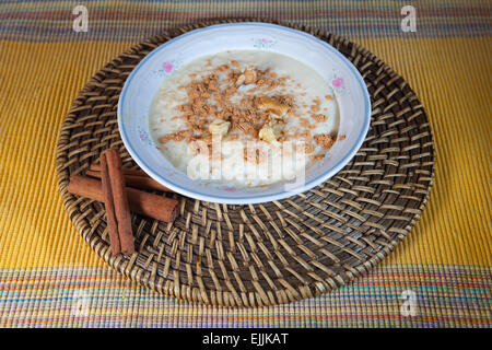 Köstliche hausgemachte Reis mit Milch und Zimt in einer Schüssel China über Naturfaser Tischset Stockfoto