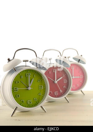 Daylight Saving Time Konzept mit drei bunten Retro-Stil-Wecker auf weißem Holz Hintergrund. Stockfoto