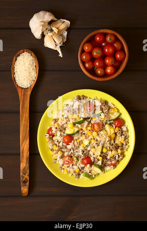 Overhead Schuss Reisgericht mit Hackfleisch und Gemüse (Mais, Cherry Tomaten, Zucchini, Zwiebel) auf Teller serviert Stockfoto