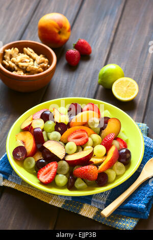 Salat von frischen Früchten gemacht von Traube, Erdbeere, Pflaume und Nektarine serviert auf Platte mit Walnüssen, Zitrone in den Rücken Stockfoto