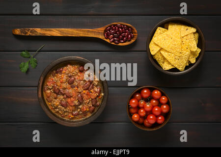 Overhead Schuss von Chili Con Carne und Tortilla-Chips mit Zutaten getrocknete Kidneybohnen und Cherry-Tomaten Stockfoto