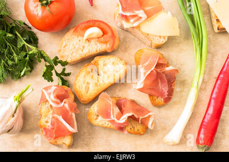 Pintxos mit Schinken, Käse, Tomaten und Knoblauch. Ansicht von oben auf einen Tisch Stockfoto