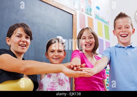 Fröhliche Gruppe vereint Studenten und Lehrer, legte ihre Hände zusammen Stockfoto