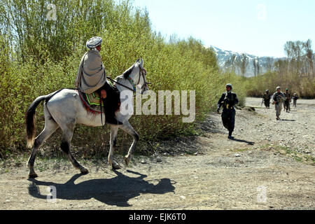 Ein afghanischer Mann reitet durch ein ausgetrocknetes Flussbett und trifft auf eine Patrouille, die unter der Leitung von US-Army Fallschirmjäger und afghanische Nationalpolizei nahe dem Dorf Bakshikhala im Kherwar Bezirk, Provinz Logar, Afghanistan, 12. April 2010. Die Fallschirmjäger sind Unternehmen C, 1. Staffel, 91. Infanterie-Regiment, 173rd Airborne Brigade Combat Team zugeordnet.  Sgt Russell Gilchrest Stockfoto