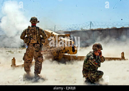 Ein US-Soldat aus Batterie B, 5. Bataillon, 25. Feldartillerie-Regiment, 4th Brigade Combat Team, 10th Mountain Division links beobachtet das Abfeuern von einer d-30 122 mm Haubitze von Afghan National Army Soldaten aus 4. Kandak, 3. Brigade, 201. Corps, während Zertifizierung Übungen auf Forward Operating Base Tagab, Kapisa Provinz, Afghanistan, 5. September 2013. Batterie B, stationiert in FOB Gamberi in Provinz Laghman, geht in Ostafghanistan, Beratung und Unterweisung Artillerie Soldaten auf die richtige Handhabung des D-30s, ein sowjetischer schwerer Artillerie Waffe in der Lage, ansprechende Ziel Stockfoto