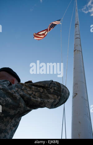 Ein Soldat rendert Ehrungen an die amerikanischen Flagge, wie es auf Halbmast zu Ehren derer, die ihr Leben verloren und wurden verletzt in Fort Hood gesenkt wird. Stockfoto