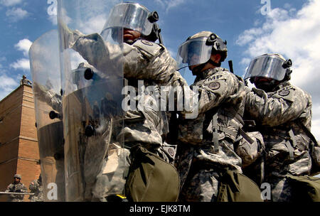 US-Armeesoldaten der 130. Military Police Company, Tennessee Army National Guard stehen in Bildung hinter der Grundlinie zu handeln als die Einheit Suche und Team zu erholen, während das Gerät eine Menge Lehrer Rollenspiel als Randalierer in Ausbildung bei der Muscatatuck Urban Training Center, ind., 25. August 2007 verteilt. Die Soldaten sind Schulungen für eine baldige Entsendung in den Kosovo.  SPC. Jerome Bischof veröffentlicht Stockfoto