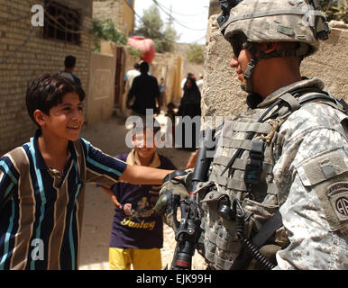 US Army Staff Sgt Antonio Alvarado Witze mit zwei irakischen Jungen während einer Patrouille durch den Adhamiyah Bezirk von Bagdad, Irak, am 10. August 2007.  Alvarado ist beigefügt, Bravo Batterie, 2nd Battalion, 319th Airborne Field Artillery Regiment.   Sgt. Jeffrey Alexander, US-Armee. Stockfoto