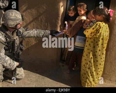 US Army 1st Lt. Michael Miller, Delta Gesellschaft, 27. Kavallerie-Regiment, 4th Brigade Combat Team, 1. Kavallerie-Division, händigt Papier für irakische Kinder während des Betriebs am Stadtrand von Mosul, Irak, 17. September 2007.  Flieger 1. Klasse Christopher Hubenthal Stockfoto