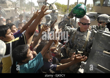 US Armee Sgt. 1. Klasse David Richardson, 1. Staffel, 89. Kavallerie-Regiment, 2nd Brigade Combat Team, 10th Mountain Division händigt Fußbälle für Kinder in Bagdad, Irak, 29. September 2007.  Techn. Sgt Andrew M. Rodier Stockfoto