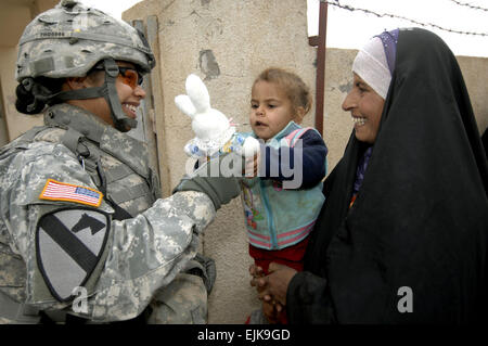 US Army Spc. Deidre Olivas Hände ein irakischen Kind wartet medizinische Behandlung ein Stofftier während einer kombinierten medizinische Mission in Quadria, Irak, 7. Dezember 2007. Olivas ist von Forward Support Truppe, 1. Staffel, 7. Kavallerie-Regiment.  Techn. Sgt. William Greer Stockfoto