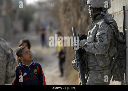 US-Armee Pfc William Felton, einen Signal-Support-Spezialisten von Headquarters und Headquarters Company, 1. Bataillon, 14. Infanterie-Regiment, 2nd Stryker Brigade Combat Team, 25. Infanterie-Division, Gespräche mit einheimischen Kindern während einer angehaltenen Patrouille in Tarmiya, Irak, 17. Februar 2008.  Techn. Sgt. William Greer Stockfoto