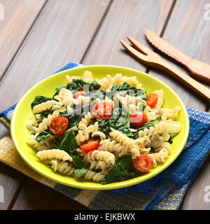 Fusilli Nudeln mit Mangoldblätter (lat. Beta Vulgaris) und Cherry-Tomaten auf Teller serviert mit hölzernen Gabel und Messer im Rücken Stockfoto