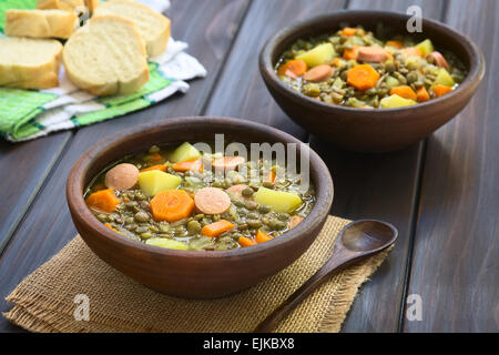 Zwei rustikale Schalen mit Linsensuppe gemacht mit Kartoffel, Karotte, Zwiebel und Wurst Scheiben mit Scheiben Baguette-Brot in den Rücken Stockfoto