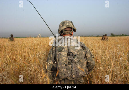 Ein US-Soldat mit Alpha-Batterie, 2. Bataillon, 15. Feld-Artillerie-Regiment 10. Mountain Division Light Infantry kreuzt ein Feld in einer Kooperation mit Soldaten der irakischen Armee mit 2. Bataillon, 4. Brigade, 6. irakischen Armee-Division in Mahmudiyah, Irak, 2. Mai 2007.  Sgt. Jacob H. Smith Stockfoto