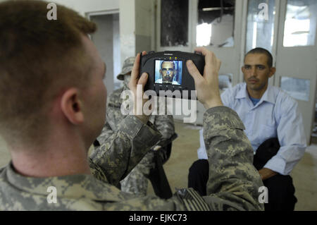 Ein Soldat der US-Armee verwendet einen handheld interagency Identität Detektoren um Fingerabdruck und Foto neue irakische Polizei Rekruten in die IP-Akademie in Mahmudiyah, Irak, 30. Mai 2007.  Der Soldat ist ab dem 2. Mannschaft, 1. Zug, 23. Military Police Company, 89. Military Police Brigade, Sitz in Fort Bragg, N.C.  Staff Sgt Dennis J. Henry Jr.. Stockfoto