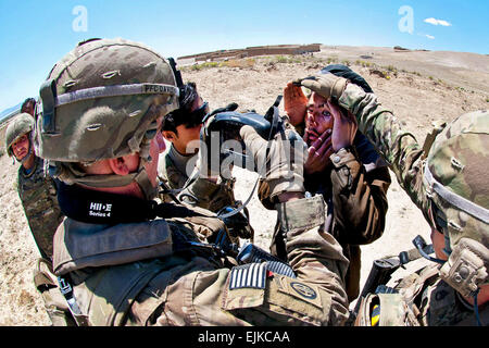 Schützen Sie PFC. Patrick Davis und Staff Sgt Joshua Tyree, Fallschirmjäger mit der 82nd Airborne Division 1st Brigade Combat Team, ein Afghane Augen vor grellem Sonnenlicht wie Davis seine Iris mit einem Handheld Interagency Identität Detektoren oder HIIDE, System-während ein afghanischer Führung Patrouille 29. April 2012, Provinz Ghazni, Afghanistan Scans.  Durch seine Iris scannen und mit dem gleichen System von Fingerabdrücken, können die Soldaten sagen, ob der junge Mann aufgezeichnet wird, als die Aufständischen Aktivitäten beteiligt.   Sgt. Michael J. MacLeod Stockfoto