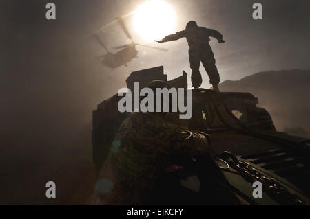 US Army Staff Sgt Hector Hoyas, Aerial Delivery Service Feldabteilung Ausbilder aus Fort Lee, VA., Wellen aus einem Nevada Army National Guard 1/189 Aviation Company CH-47 Chinook-Hubschrauber als US Air Force Piloten von 820th Red Horse Geschwader in der Luft Flug sichern den Spiegel vor dem Einhängen der Humvee bis zu der Chinook für Schlinge Last auf Nellis Air Force Base , Nevada, 15. April 2011. Stockfoto