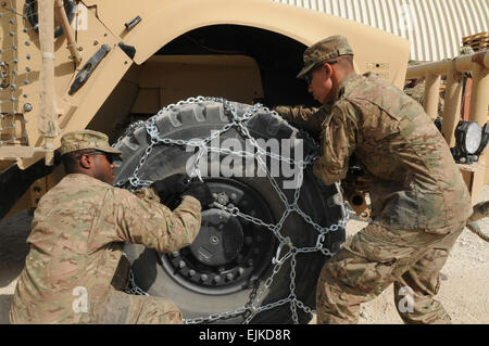 PFC. Val J. Irick links, ein Eingeborener von Daytona Beach, Florida, und Pfc. Ryan M. Sindle Recht, gebürtig aus Elkhart, Indiana, beide Soldaten mit der Task Force Lifeliner Befehl Sicherheits-Team legen fest eine Schneekette auf eine Mine-resistente Hinterhalt geschützt Fahrzeugreifen im Rahmen des Winter Training Klasse, 26. Oktober 2013, Bagram Airfield in Parwan Provinz, Afghanistan. Diese Ausbildung lehrt den Soldaten wie Sie richtig Schneeketten auf Reifen und wie ihre Fahrzeuge bei kalter Witterung zu bedienen. Bildnachweis: Sgt. Sinthia Rosario, Task Force Lifeliner Public Affairs 131026-A-ZT122-081 Stockfoto