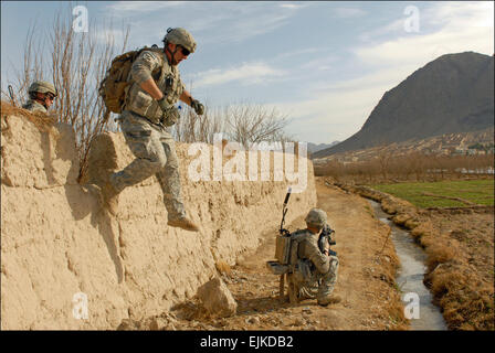 US-Armee Pfc. Andrew Ballard springt von einem Schlamm-Mauer während seiner Mannschaft Sicherheit während einer Fuß-Patrouille im Arghandab Bezirk, Afghanistan, 31. Januar 2011 zieht. Ballard, zugeordnet der 4. Infanterie-Division Unternehmen C, 1. Bataillon, 66th Armored Regiment, 1st Brigade Combat Team, war die Durchführung der Fuß Patrouille um Obstgärten im ganzen Distrikt suchen und interagieren mit den Bewohnern.  SPC. Breanne Pye Stockfoto