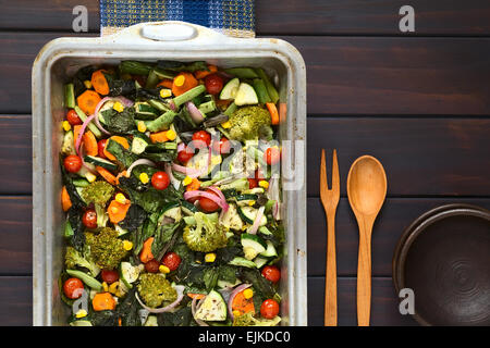 Overhead Schuss gebackenes Gemüse (Zucchini, Zwiebel, Cherry Tomaten, Brokkoli, Karotten, Mais, grüne Bohnen, Mangold) Stockfoto