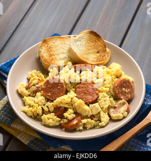 Rührei mit Chorizo-Scheiben und Zwiebel auf Teller mit geröstetem Baguette Scheiben, fotografiert mit natürlichem Licht gemacht Stockfoto