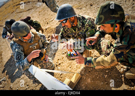 US Armee Sgt. 1. Klasse John Haidu, Mitglied der Vereinigte Staaten Armee Treffsicherheit Einheit von Phenix City, Ala., hört, wie ANA Schüler-Lehrer erklären, warum ihre Ziel-Gruppierung ausgeschaltet ist und wie man es in die grundlegende Gewehr Treffsicherheit Instructor Kurs in Kabul Military Training Center, Afghanistan, 6. November 2010 zu korrigieren. Nach dem zehn-Tage-Kurs werden die Soldaten ANA Auszubildende in grundlegenden Treffsicherheit anweisen können. SAF-Foto von US Air Force Staff Sgt Joseph Swafford Stockfoto