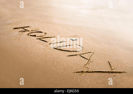 Urlaub-Wort geschrieben auf dem hellen Sand zurück Lichteffekt Stockfoto