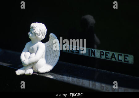 Kleine Engel sitzend auf Sockel aus schwarzem Granit Grabstein mit Inschrift "Rest in Peace" Stockfoto