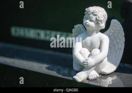 Kleine Engel sitzend auf Sockel aus schwarzem Granit Grabstein mit Inschrift "Rest in Peace" Stockfoto