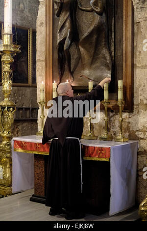 Ein Franziskanermönch zündet Kerzen über dem Altar Mariens an Magdalena in der Kapelle Maria Magdalena in der Kirche von Heilige Grab alte Stadt Ost-Jerusalem Israel Stockfoto