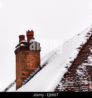 Alte Haus Lehm gemauerten Kamin im Winter mit Schnee bedeckt Stockfoto