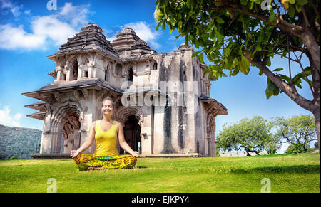 Frau beim Yoga in der Nähe von Lotus Mahal im königlichen Center am blauen Himmel in Hampi, Karnataka, Indien Stockfoto