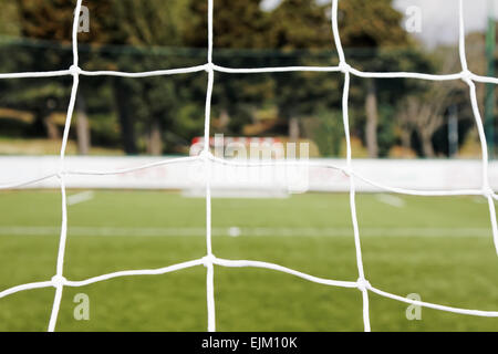 Blick vom Fußballnetz und unscharfen Tor gegen Stockfoto