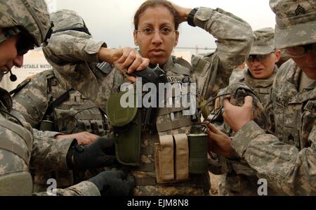 US-Armeesoldaten unterstützen Staff Sergeant Enorita Marshall beim straffen Körper Rüstung vor der Abreise für eine Suche nach den Überresten eines fehlenden Soldaten Februbary 22, 2007 in Bagdad, Irak. Stockfoto