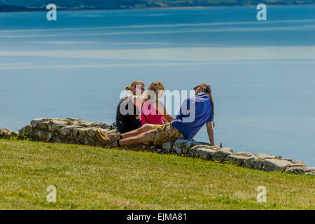 Drei junge Leute, Sonnenbaden in Criccieth Schloß, North Wales, Gwynedd, Vereinigtes Königreich Stockfoto