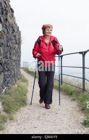 Aktive ältere Frau Wanderweg Nordic walking auf felsigen im Freien. Stockfoto
