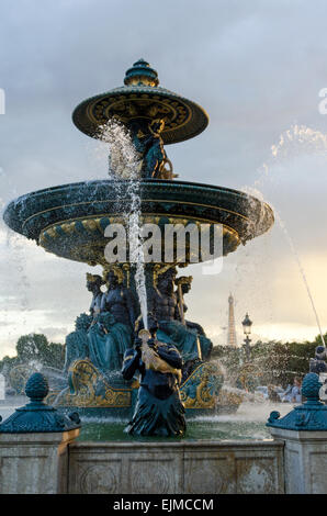 Die Fontaine des Fleuves bei Sonnenuntergang in der Place De La Concorde, Paris, Frankreich, mit dem Eiffelturm in der Ferne. Stockfoto